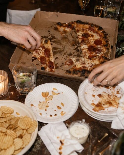 A pizza box, paper plates and crinkle-cut chips on a table