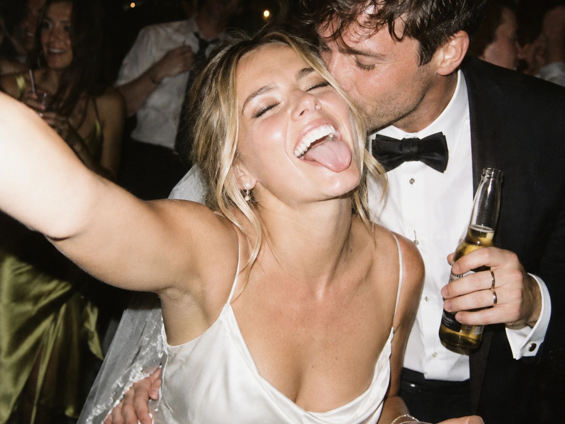 A bride kissed on the cheek, arm outstretched