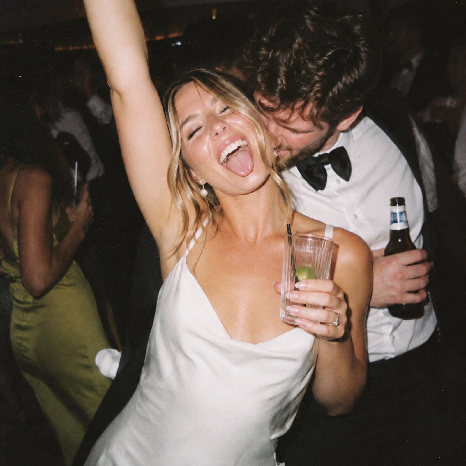 A bride throwing her arm up, drink in hand