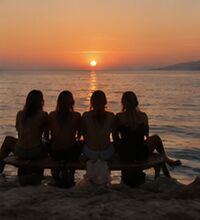 Four friends on a bench watching the sunset