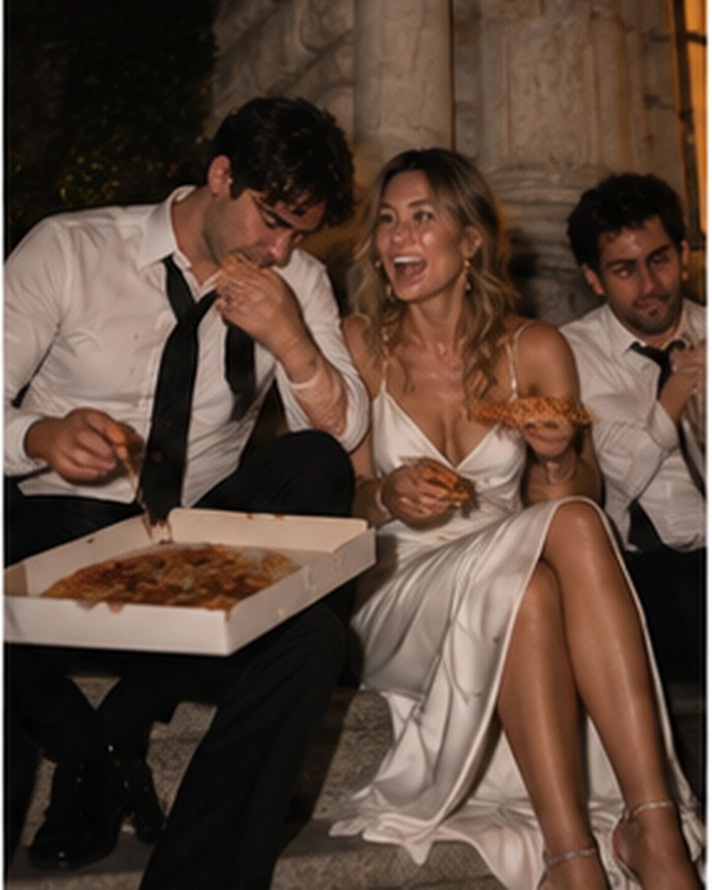 A couple sharing pizza on the steps outside