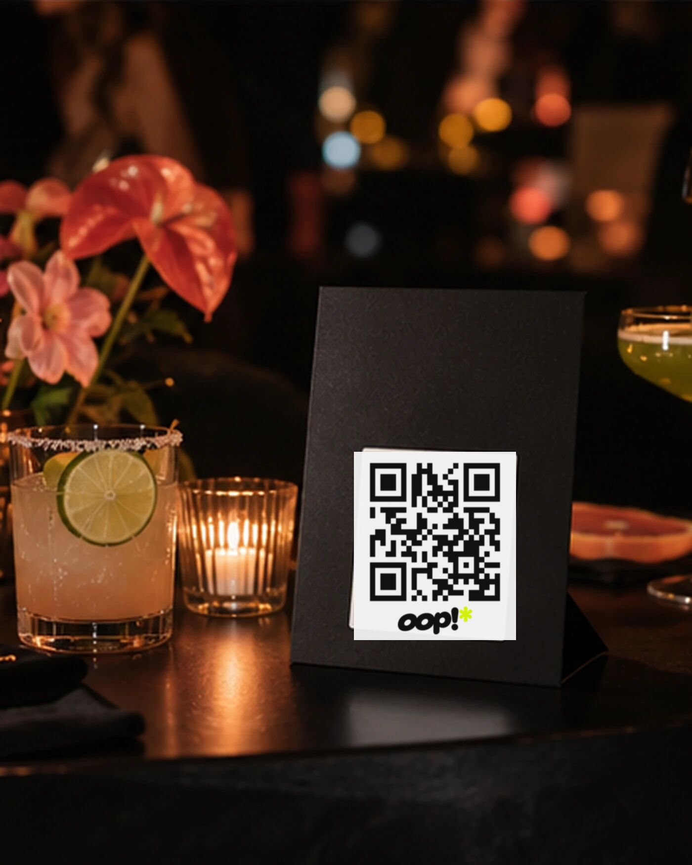 An oop QR card on a dark table among cocktails