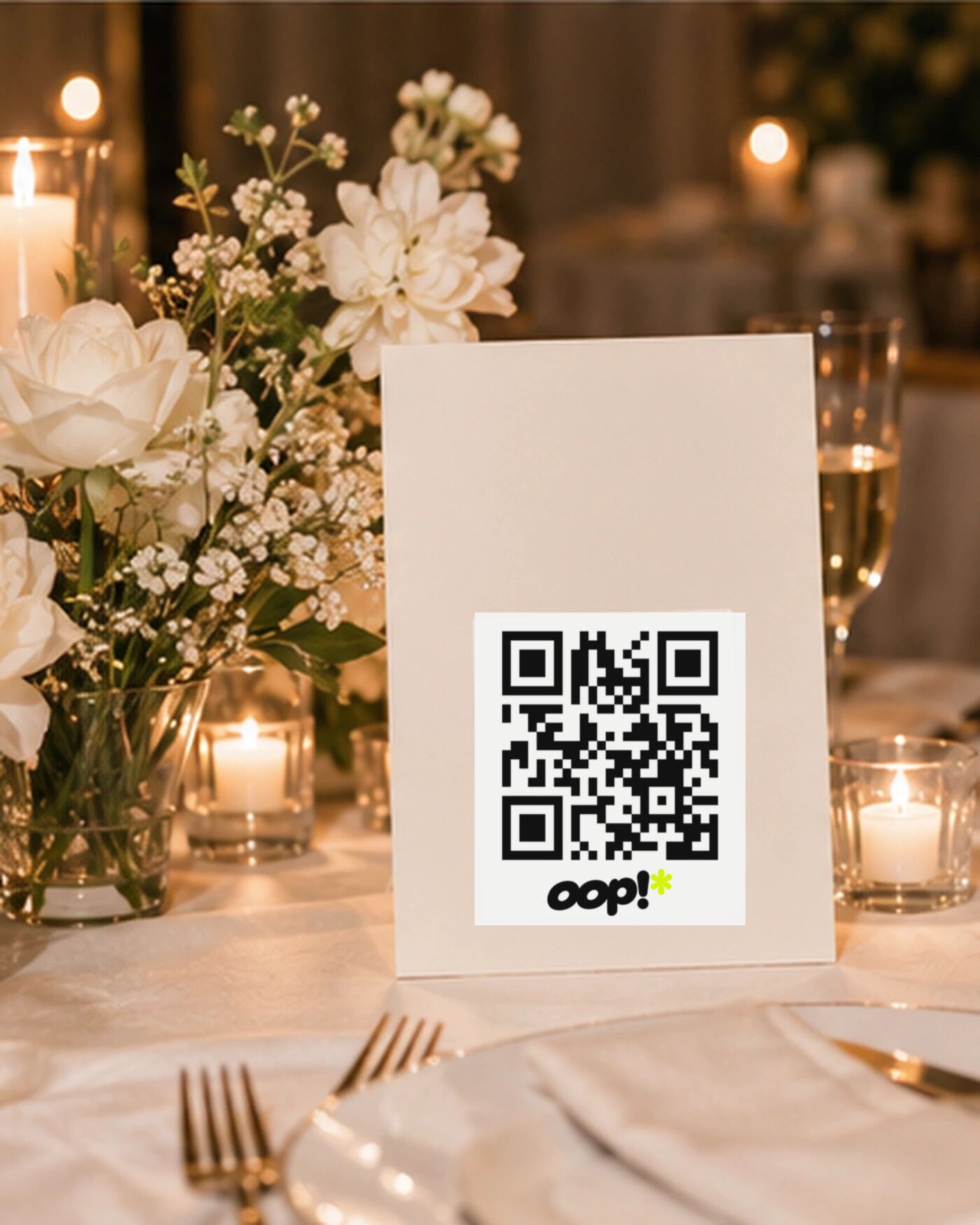 An oop QR card standing on a candlelit wedding table among flowers