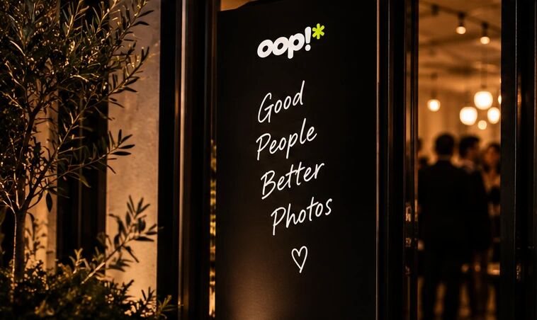 A black oop welcome sign at a venue entrance reading “Good People Better Photos”